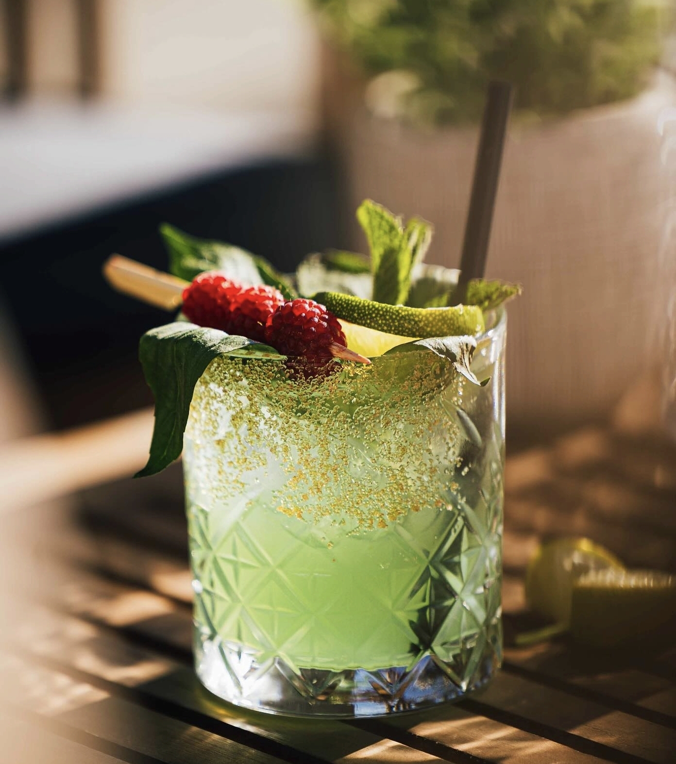 Cocktail frais aux fruits rouges, citron vert et feuilles de menthe dans la lumière du soleil